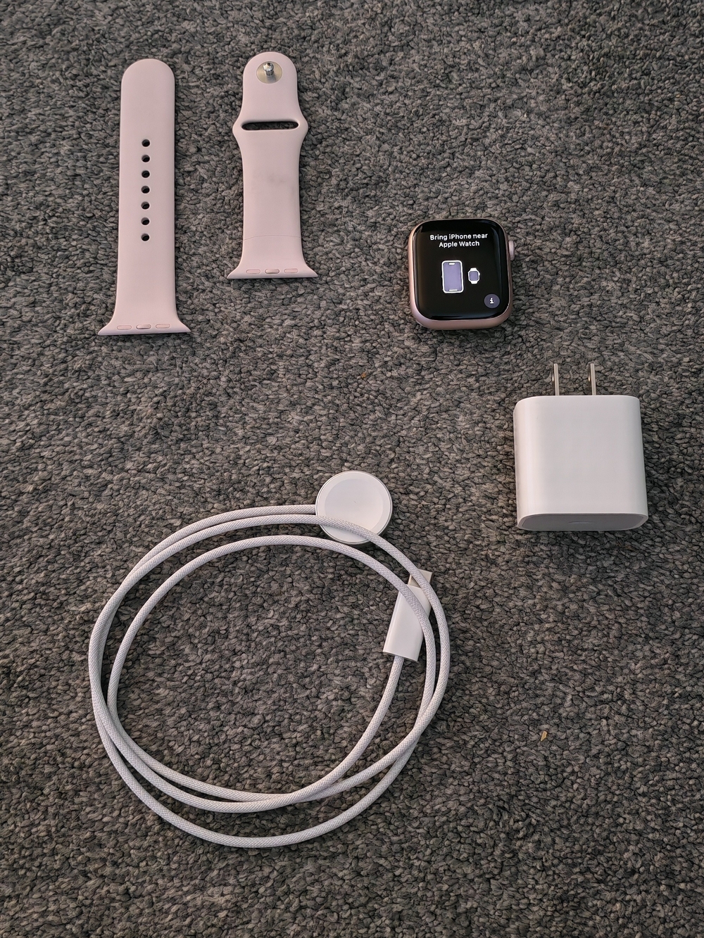 Apple Series 9 Watch with Pink Sport Band and White Charger.